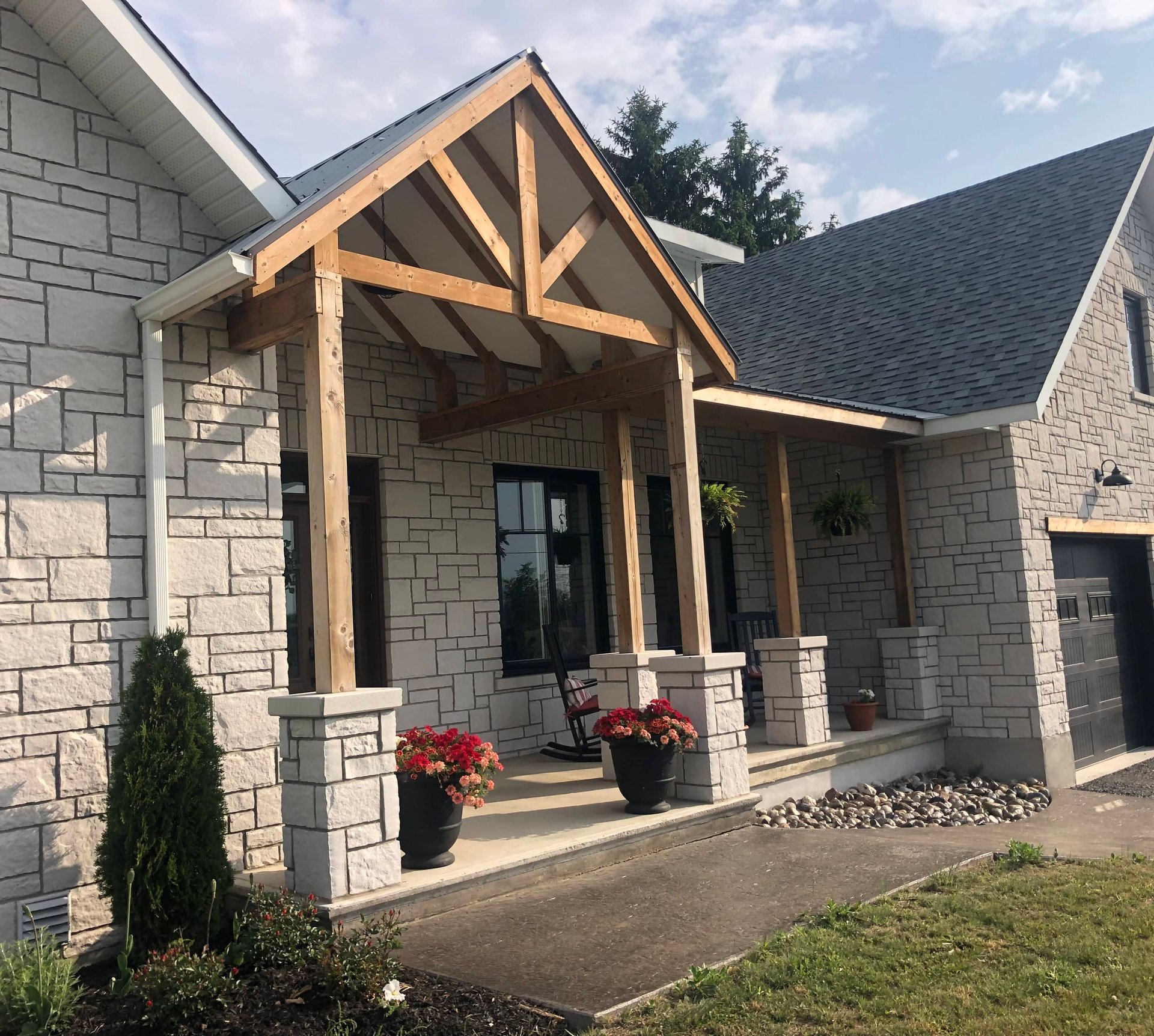 A white stone veneer house with a concreate pad step